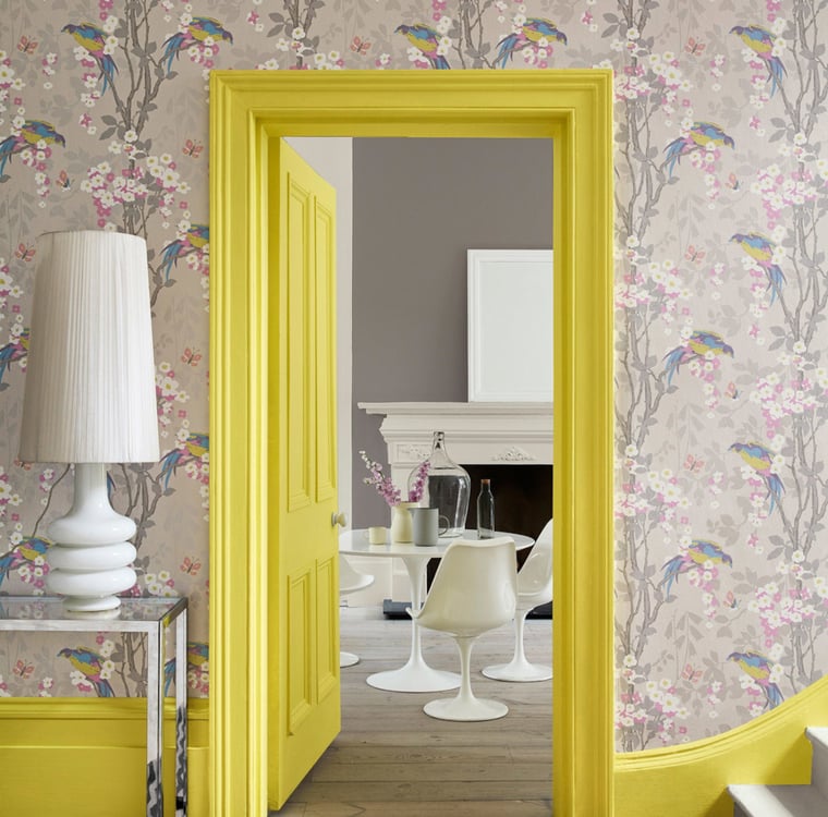 Room with a wallpaper with a bird motif and a yellow painted door frame